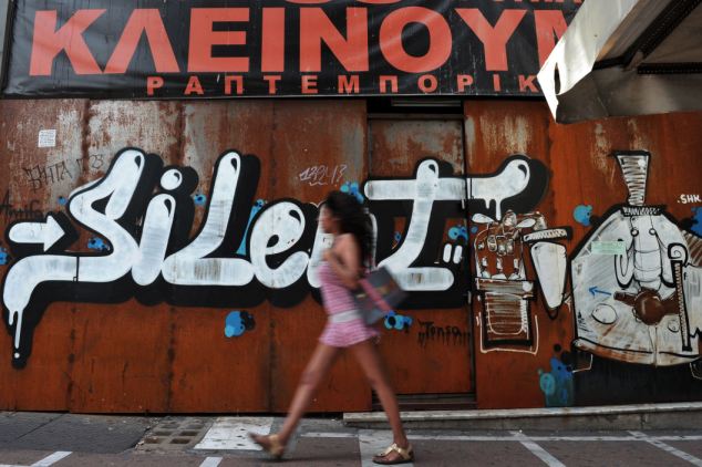 Slump: A woman walks past a shut down store in Athens - the economy is expected to slump by 4.2 to 4.5 percent this year