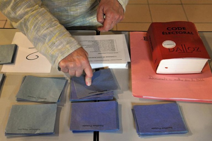 A volunteer counts voting envelopes during the first round of local elections at a polling station A volunteer counts voting envelopes during the first round of local elections at a polling station