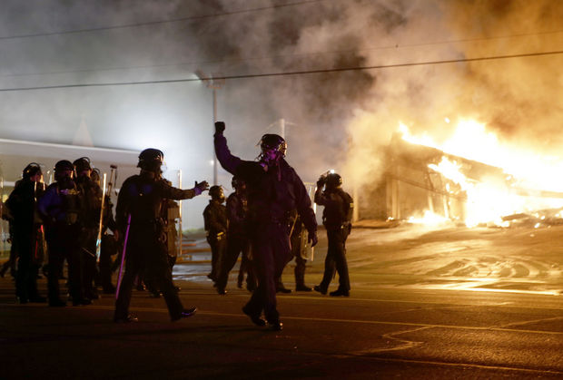 Police standing in front of a fire trying to stop more fires from being started