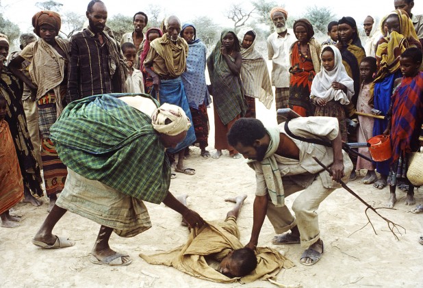 August 1992 - Berdale, Somalia - A starving child, so weak from hunger that he collapsed, is helped to his feet at Berdale. Photo Credit: ANDREW HOLBROOKE/CORBIS