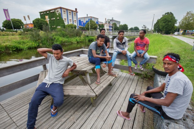 24-07-2015 kanaal vlakbij speelstad oranje waar 700 vluchtelingen wonen. Bewoners zijn bang dat kinderen van asielzoekers niet kunnen zwemmen en in het kanaal verzuipen. Nu is er extra toezicht. Vanmiddag was er geen toezicht en geen kinderen te zien. Foto: Samiel, Efream, Mehari, Ermias, Samiel en John uit Eritrea op een van de steigers bij het kanaal. Alleen Samiel (li.) en Efream kunnen zwemmen. Maar dat hebben ze in Oranje nog niet gedaan. "Too cold". Trefwoorden: AZC, Speelstad. Fotograaf: Rens Hooyenga