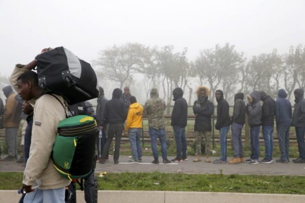Migrants carry their belongings on the third day of their evacuation and transfer to reception centers in France, as part of the dismantlement of the camp called the "Jungle" in Calais