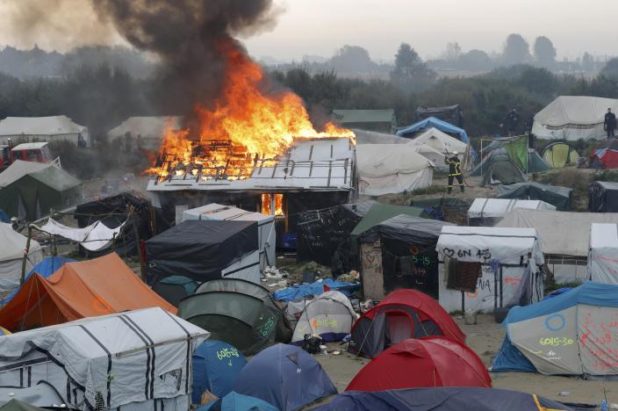 Firefighters extinguish burning makeshift shelters and tents in the "Jungle" on the third day of the evacuation of migrants and their transfer to reception centers in France, as part of the dismantlement of the camp in Calais