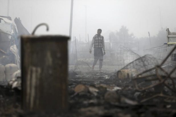 A migrants stands in the charred debris from makeshift shelters and tents in the "Jungle" on the third day of their evacuation and transfer to reception centers in France, as part of the dismantlement of the camp in Calais