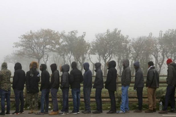 Migrants queue on the third day of their evacuation and transfer to reception centers in France, as part of the dismantlement of the camp called the "Jungle" in Calais