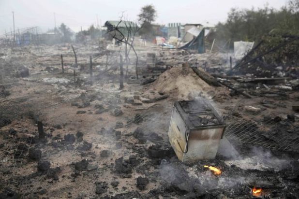A gas cooker is seen in the charred debris from fires that destroy makeshift shelters and tents in the "Jungle" on the third day of their evacuation and transfer to reception centers in France, as part of the dismantlement of the camp in Calais