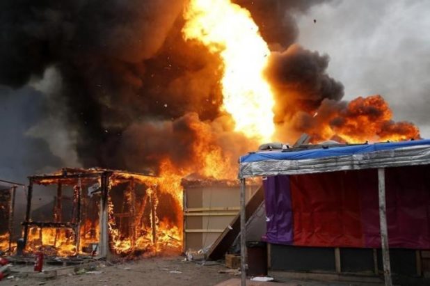 Flames from makeshift shelters are seen during the explosion of a gas bottle in the "Jungle" on the third day of the evacuation of migrants, as part of the dismantlement of the camp in Calais