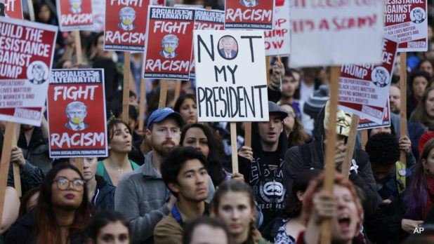 Protesters hold signs during a protest against the election of President-elect Donald Trump, Wednesday, Nov. 9, 2016, in downtown Seattle. (AP Photo/Ted S. Warren)